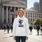 Strong woman wearing Believe Women hoodie in front of courthouse