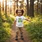 Toddler with curly pigtails wearing Little Hikers Club t-shirt on hiking trail - correct size