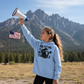 Young girl in Carolina Blue environmental protest hoodie with megaphone at national park mountain base